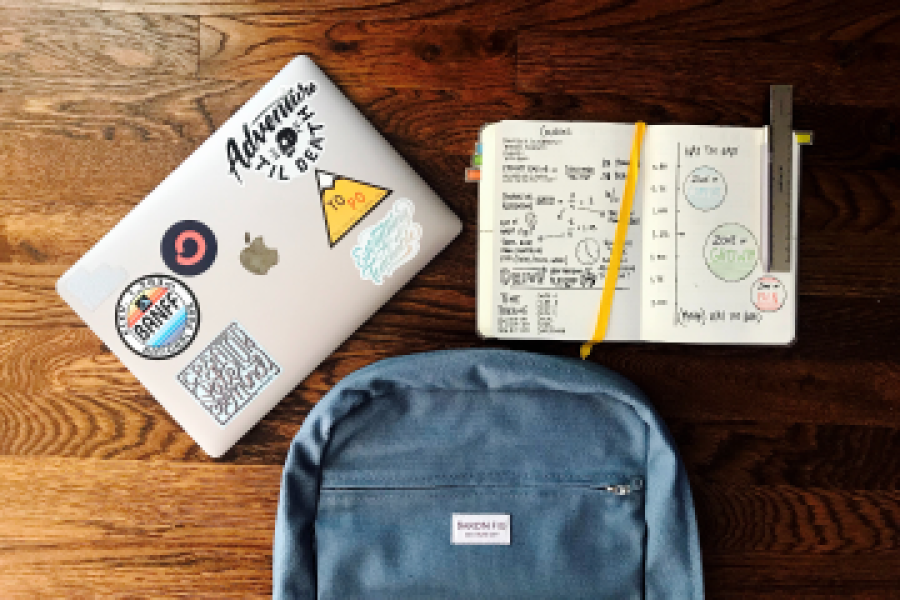 A laptop, an open notebook, and a backpack
