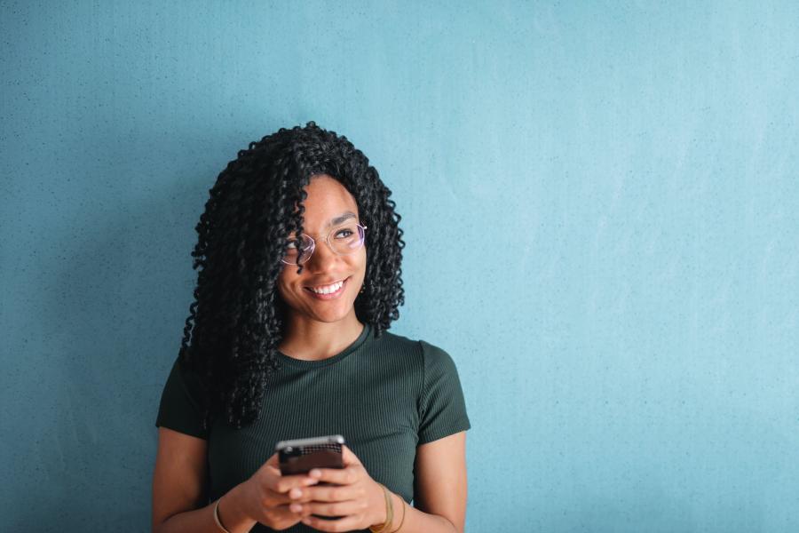 young woman smiling holding phone