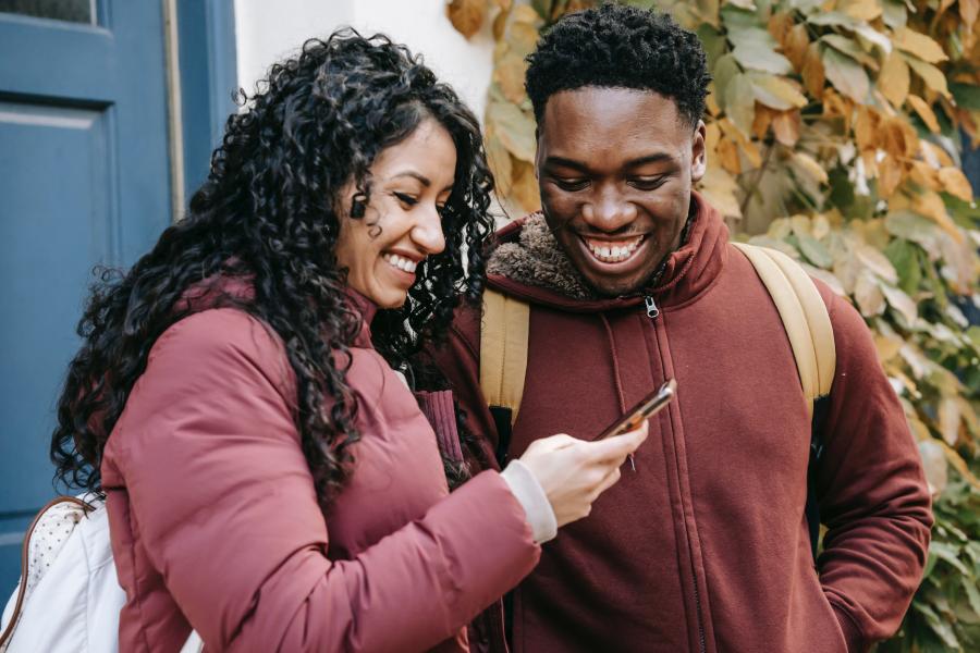 young woman and young man look at phone